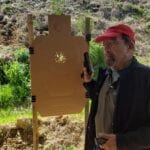 A man wearing a cap and holding a gun