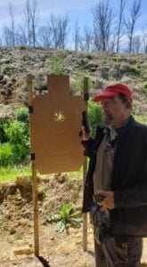 A man wearing a cap and holding a gun