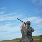 A person shooting a gun in the open sky