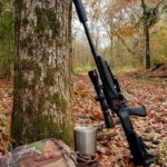 A gun standing next to a tree