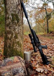 A gun standing next to a tree